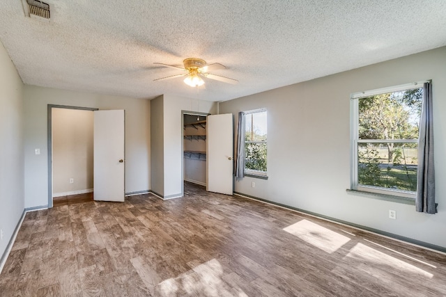 unfurnished bedroom with ceiling fan, wood-type flooring, a textured ceiling, and a closet