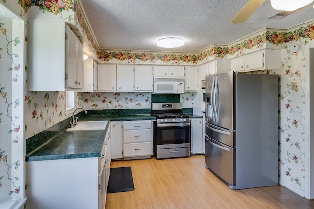 kitchen with sink, light hardwood / wood-style floors, a textured ceiling, white cabinets, and appliances with stainless steel finishes