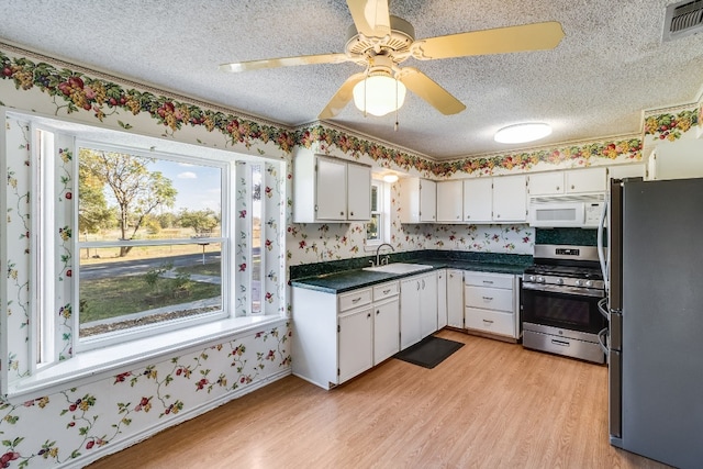 kitchen featuring ceiling fan, white cabinets, stainless steel appliances, and light hardwood / wood-style floors