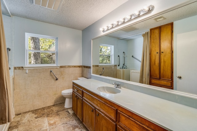 bathroom with vanity, a textured ceiling, and a healthy amount of sunlight