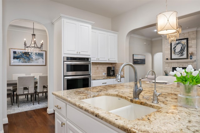 kitchen featuring decorative light fixtures, sink, and white cabinetry