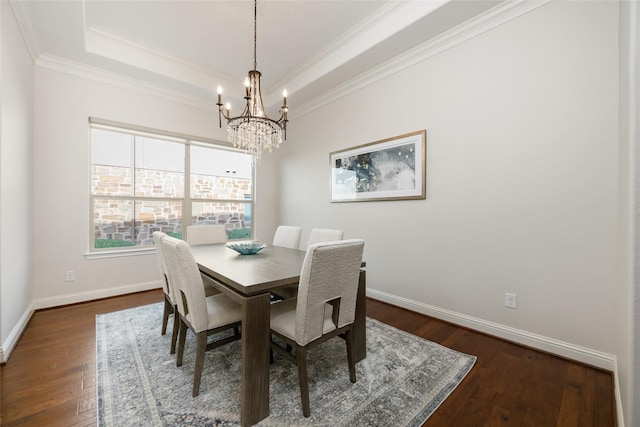 dining area with a chandelier, dark hardwood / wood-style flooring, a tray ceiling, and ornamental molding