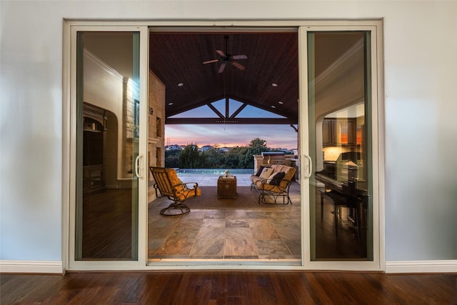 doorway with hardwood / wood-style floors, crown molding, and vaulted ceiling