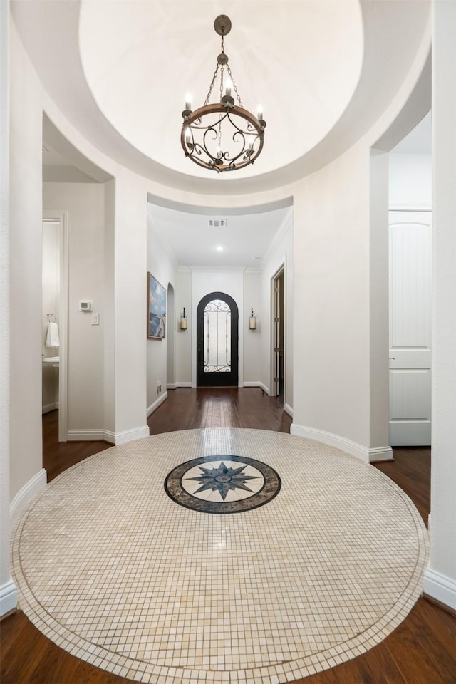 foyer featuring dark hardwood / wood-style floors, an inviting chandelier, and ornamental molding