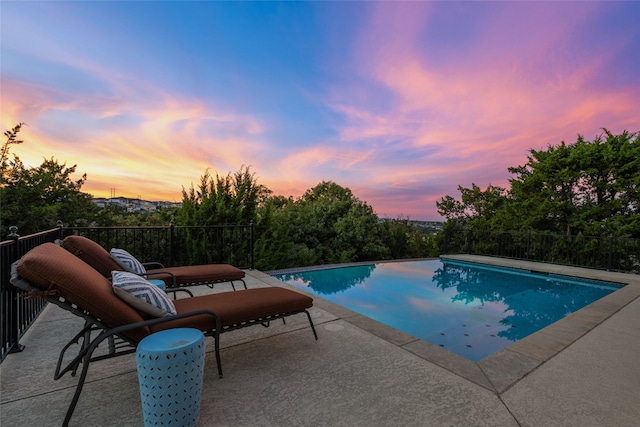 pool at dusk with a patio area