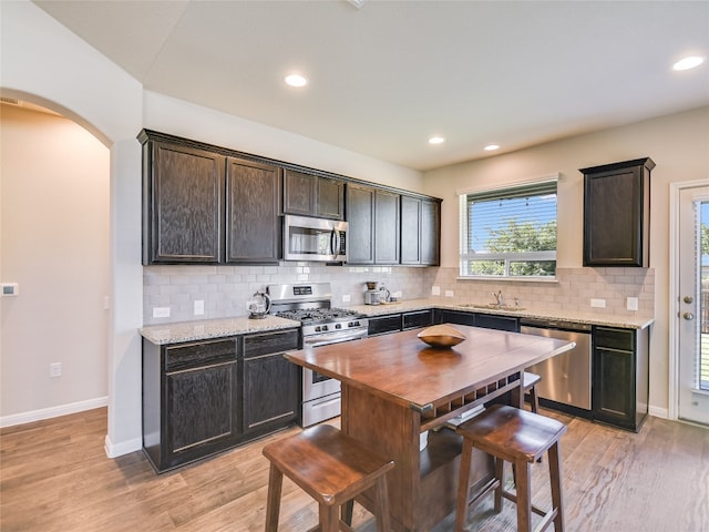 kitchen featuring backsplash, dark brown cabinetry, light hardwood / wood-style flooring, and stainless steel appliances