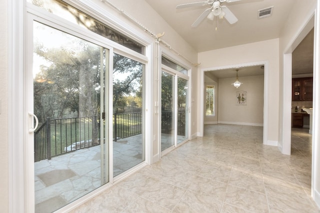 unfurnished sunroom with ceiling fan