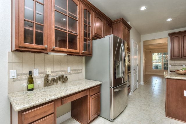 kitchen featuring decorative backsplash, light tile patterned flooring, light stone counters, and stainless steel refrigerator with ice dispenser