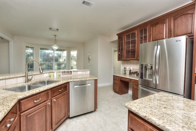 kitchen featuring light stone countertops, sink, stainless steel appliances, and decorative light fixtures