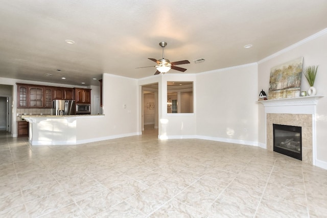 unfurnished living room with ceiling fan, crown molding, and a tiled fireplace