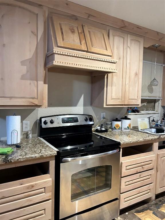 kitchen featuring electric range, light brown cabinets, light stone countertops, and sink