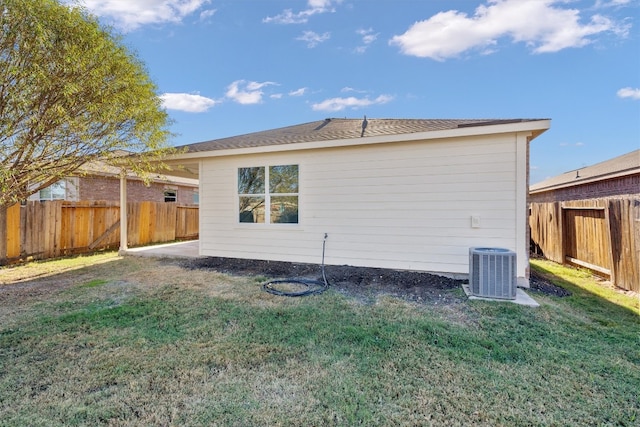 back of property featuring a lawn and central air condition unit