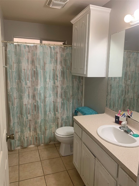 bathroom featuring toilet, vanity, tile patterned floors, and curtained shower