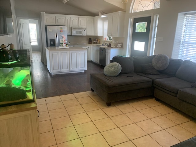 living room with sink, plenty of natural light, lofted ceiling, and light wood-type flooring