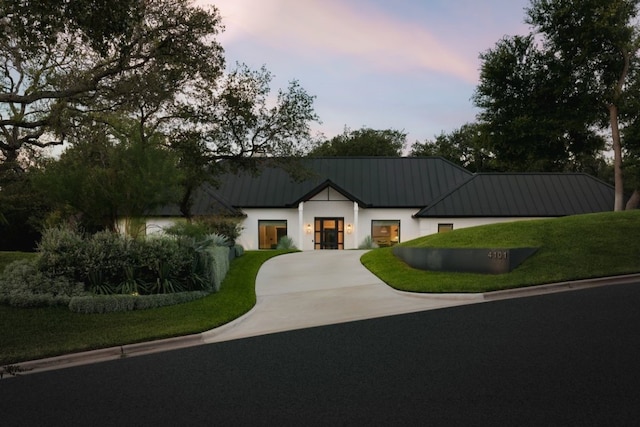 4101 Mcbrine Pl, Austin, TX 78746 - view of front facade with a standing seam roof, a metal roof, a front yard, curved driveway, and stucco siding