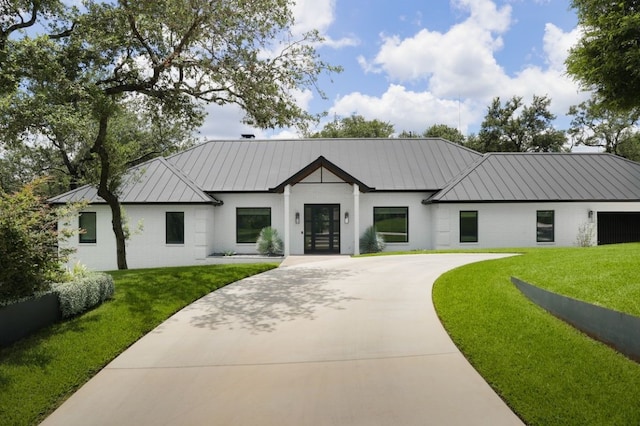 modern farmhouse featuring a garage, a front yard, and french doors