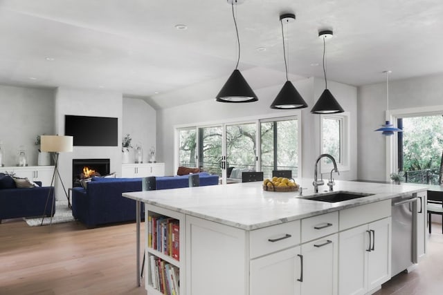 kitchen with light stone counters, white cabinetry, a wealth of natural light, and sink