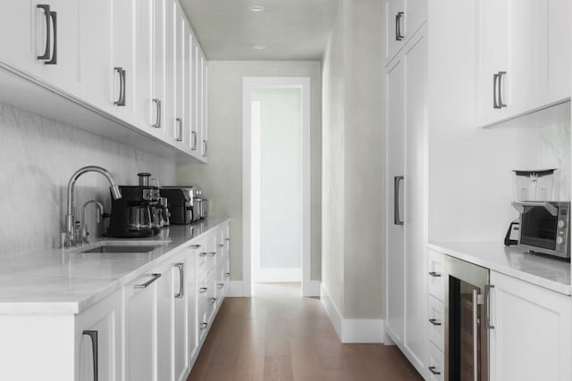 bar featuring white cabinets, hardwood / wood-style floors, beverage cooler, and sink