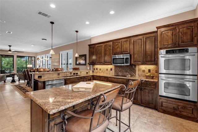 kitchen with stainless steel appliances, kitchen peninsula, decorative light fixtures, a breakfast bar, and a kitchen island