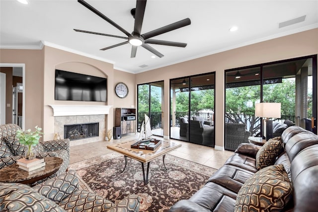 living room featuring ceiling fan, ornamental molding, a fireplace, and light tile patterned floors