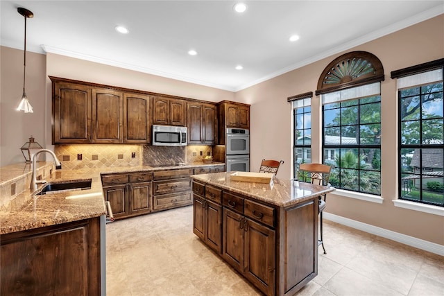 kitchen featuring sink, hanging light fixtures, stainless steel appliances, a kitchen breakfast bar, and backsplash