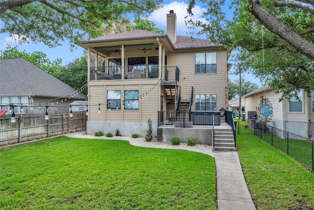 rear view of house with ceiling fan and a yard