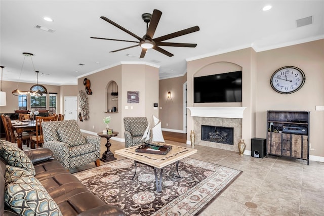 tiled living room featuring a tiled fireplace, ceiling fan, and ornamental molding