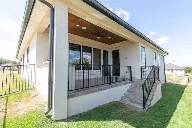 entrance to property featuring ceiling fan and a yard