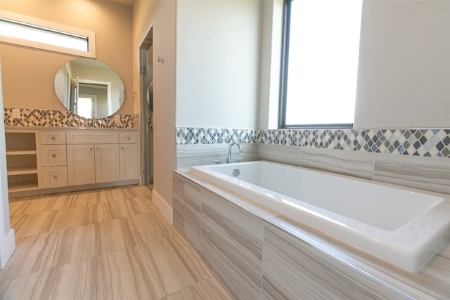 bathroom with vanity and tiled bath