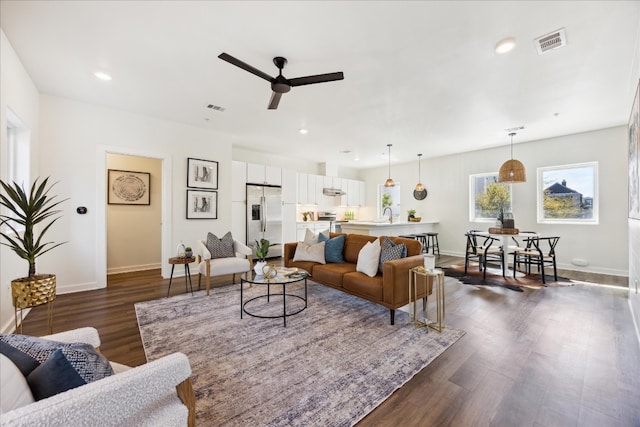 living room with dark hardwood / wood-style flooring and ceiling fan