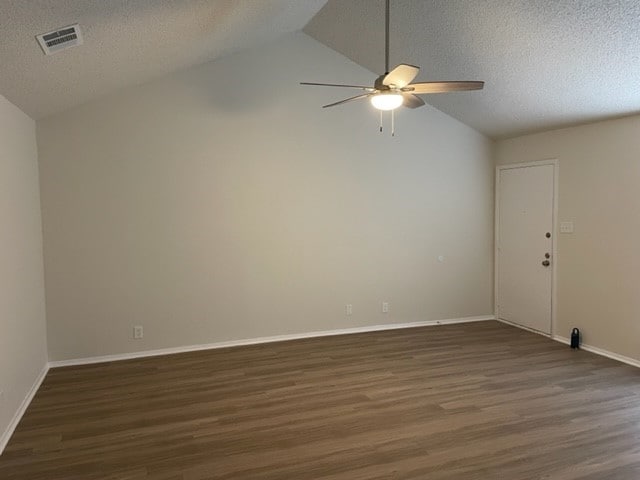 empty room with a textured ceiling, ceiling fan, dark hardwood / wood-style floors, and lofted ceiling