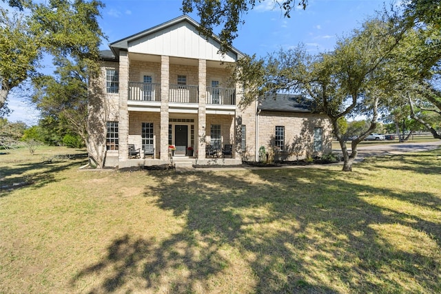 rear view of property featuring a porch, a balcony, and a yard