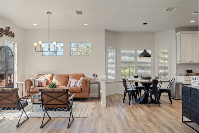 living room with an inviting chandelier, a healthy amount of sunlight, and light hardwood / wood-style floors