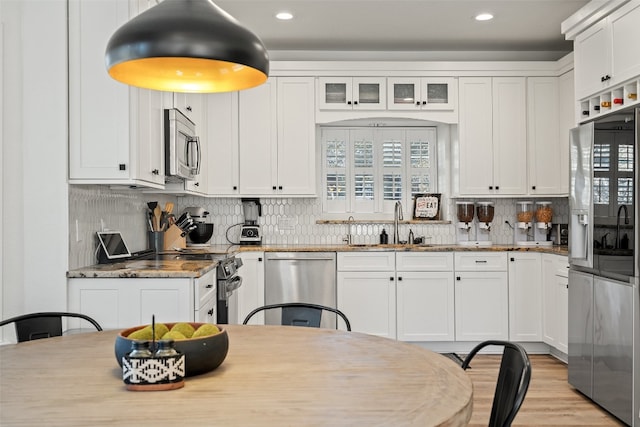 kitchen featuring white cabinets, sink, tasteful backsplash, light stone counters, and stainless steel appliances