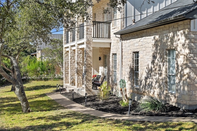 view of side of home featuring a yard and a balcony