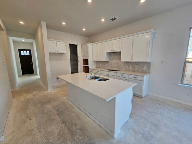 kitchen featuring tasteful backsplash, black electric cooktop, sink, white cabinets, and an island with sink