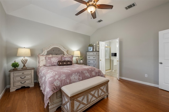 bedroom with dark hardwood / wood-style flooring, vaulted ceiling, ceiling fan, and connected bathroom