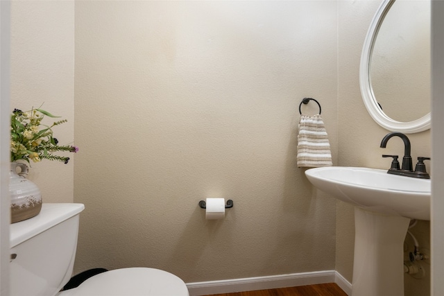 bathroom with toilet, wood-type flooring, and sink