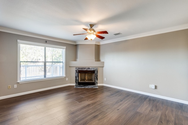 unfurnished living room with ceiling fan, ornamental molding, dark wood-type flooring, and a high end fireplace