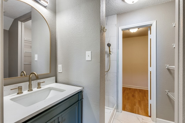 bathroom with hardwood / wood-style flooring, vanity, a textured ceiling, and walk in shower