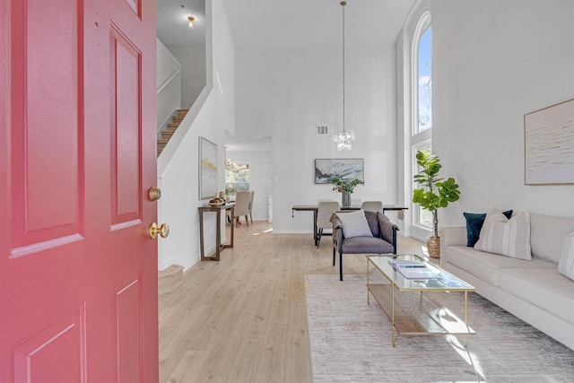 foyer with an inviting chandelier, a high ceiling, and light wood-type flooring