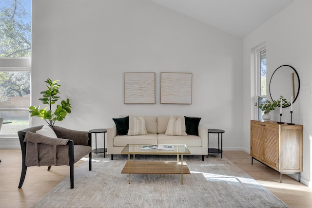 living room with lofted ceiling, a healthy amount of sunlight, and light wood-type flooring