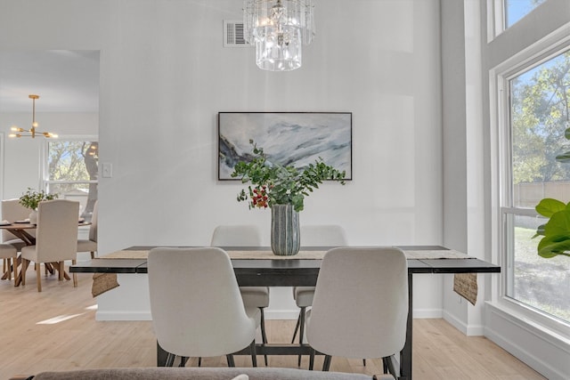 dining space featuring light wood-type flooring and an inviting chandelier