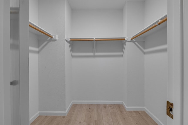 walk in closet with light hardwood / wood-style floors