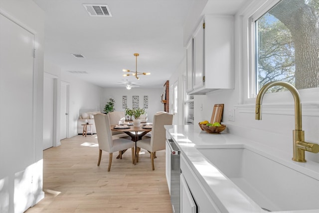 kitchen featuring decorative light fixtures, dishwasher, sink, and white cabinets