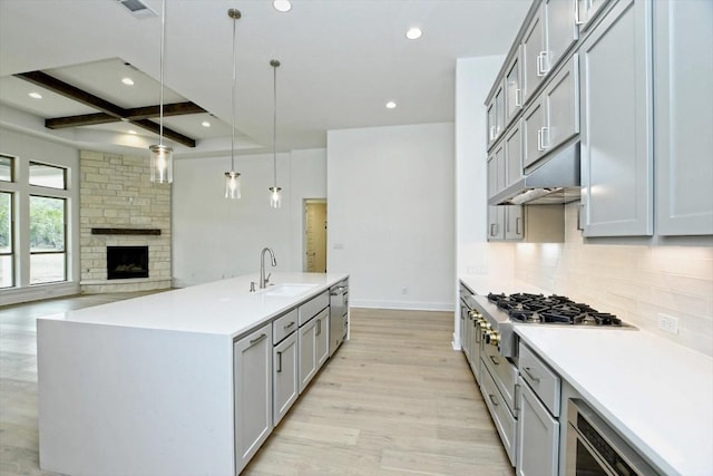 kitchen with pendant lighting, sink, a kitchen island with sink, beam ceiling, and stainless steel gas cooktop