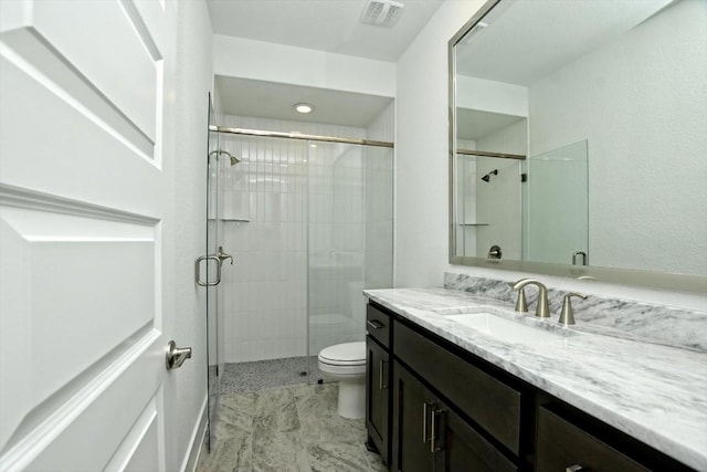 bathroom featuring vanity, a shower with shower door, and toilet