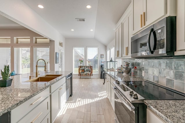 kitchen with appliances with stainless steel finishes, vaulted ceiling, sink, light hardwood / wood-style floors, and white cabinetry