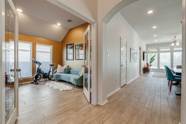 corridor with french doors, light hardwood / wood-style floors, and lofted ceiling