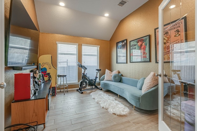 living area featuring light wood-type flooring, french doors, and vaulted ceiling